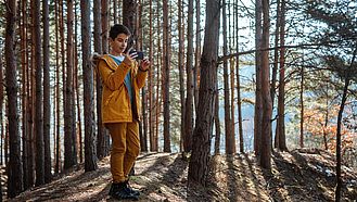 Junge mit Smartphone im Wald